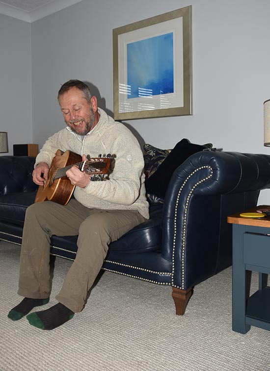 simon onions playing guitar on his couch